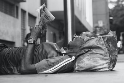 躺在人行道上看报纸的男子